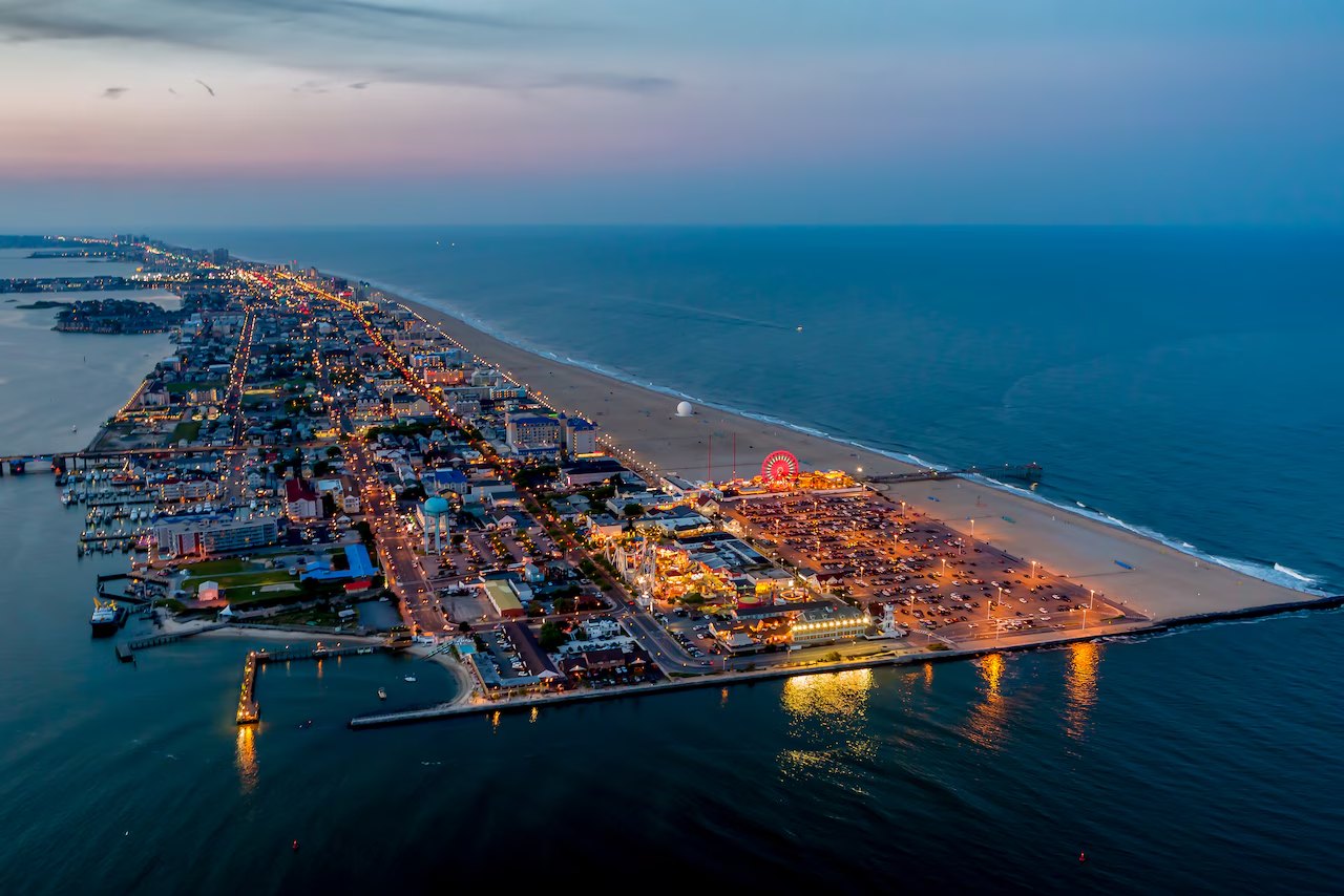 Ocean City, Maryland at dusk — lit boardwalk and Ferris wheel from the air